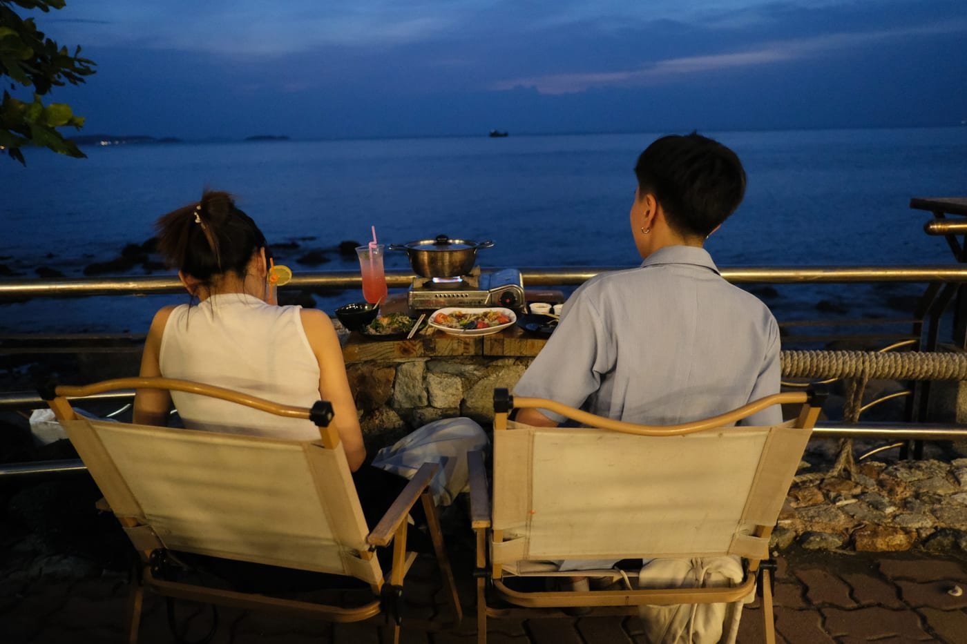 Smiling romantic couple enjoying a scenic seaside twilight dinner date with cocktails