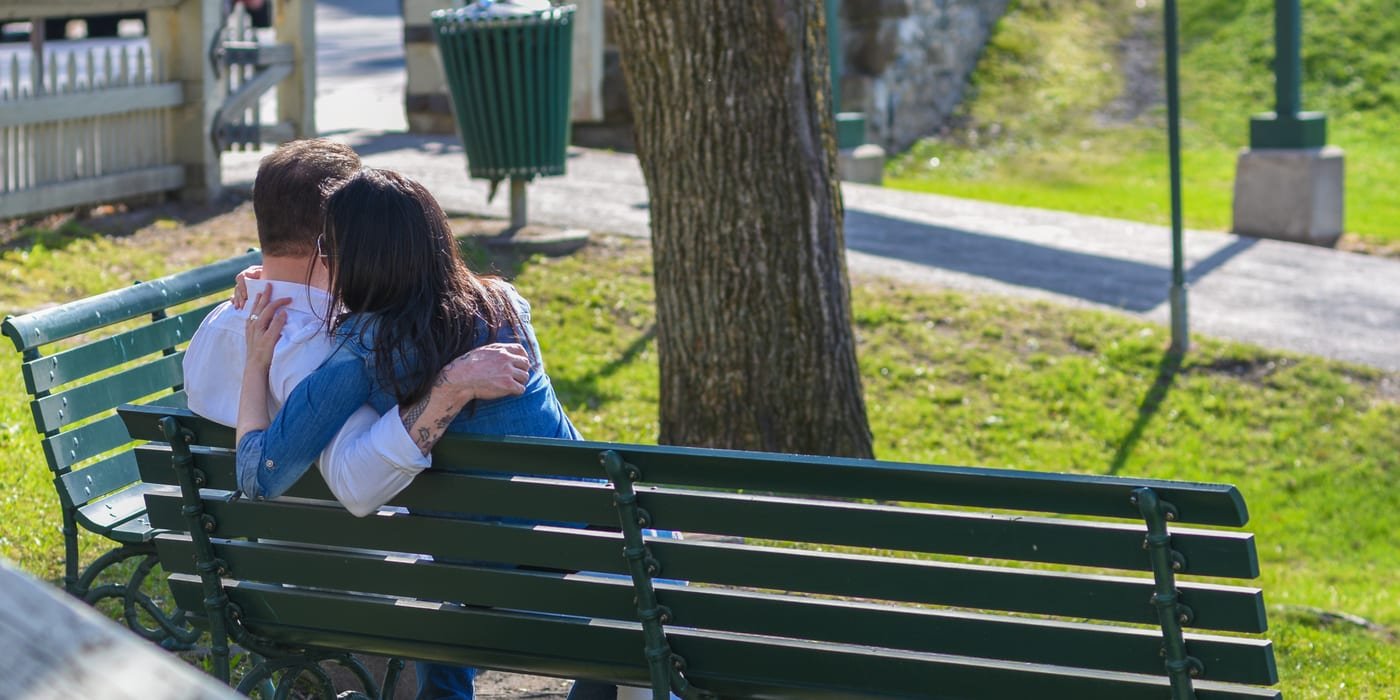 Compassionate romantic couple sitting closely on a bench sharing an understanding conversation about HSV virology and relationship trust